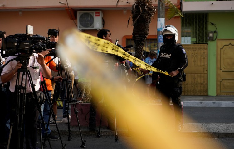 Journalists stand behind a police tape at a crime scene in Guayaquil, Ecuador, on November 1, 2022.