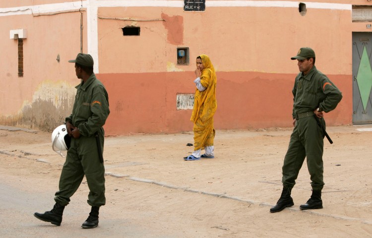 A Sahrawi woman walks near Moroccan police in Laayounne in the disputed territory of Western Sahara in 2005.